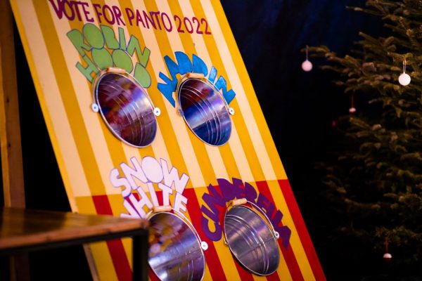 Panto voting booth with four buckets recessed into a piece of wood painted with stripes