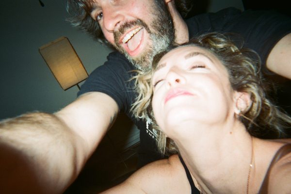 A man and a woman smile at the camera in a close up, high angle selfie.