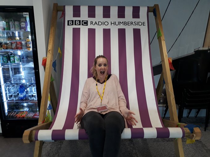 A young white woman sat in a giant striped deckchair branded with BBC Radio Humberside